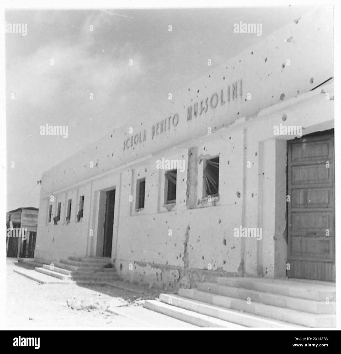 Les soldats puisent de l'eau devant une école italienne avec des murs endommagés par la bataille pendant les opérations de l'armée britannique. Banque D'Images