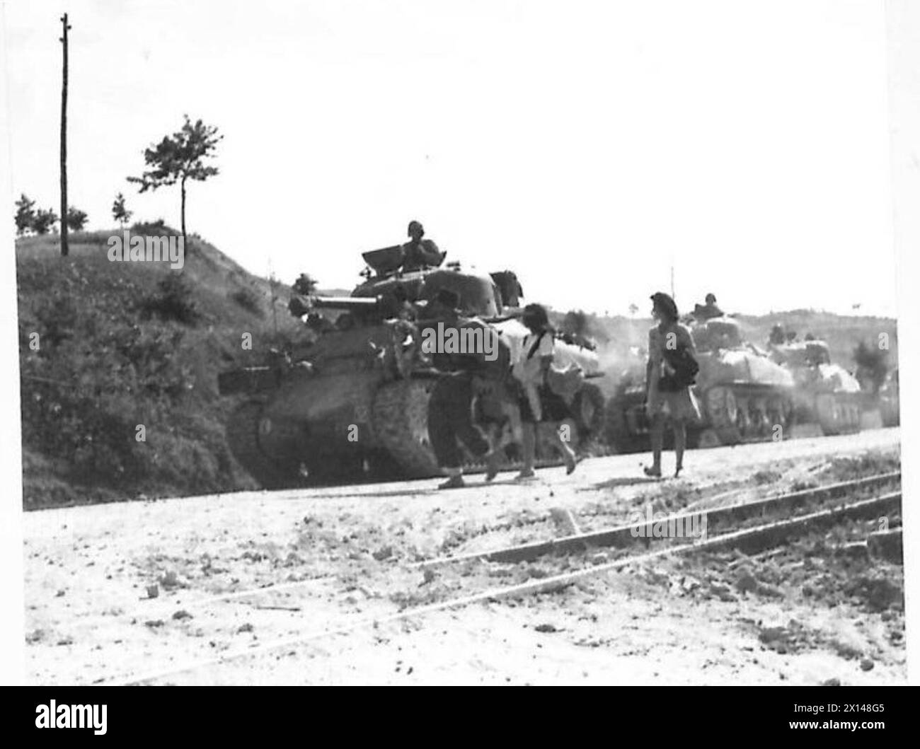 HUITIÈME ARMÉE : DIVERS - chars alignés au bord de la route, attendant d'utiliser une diversion autour d'un pont démoli. Trois réfugiés italiens passent à pied à l'armée britannique Banque D'Images