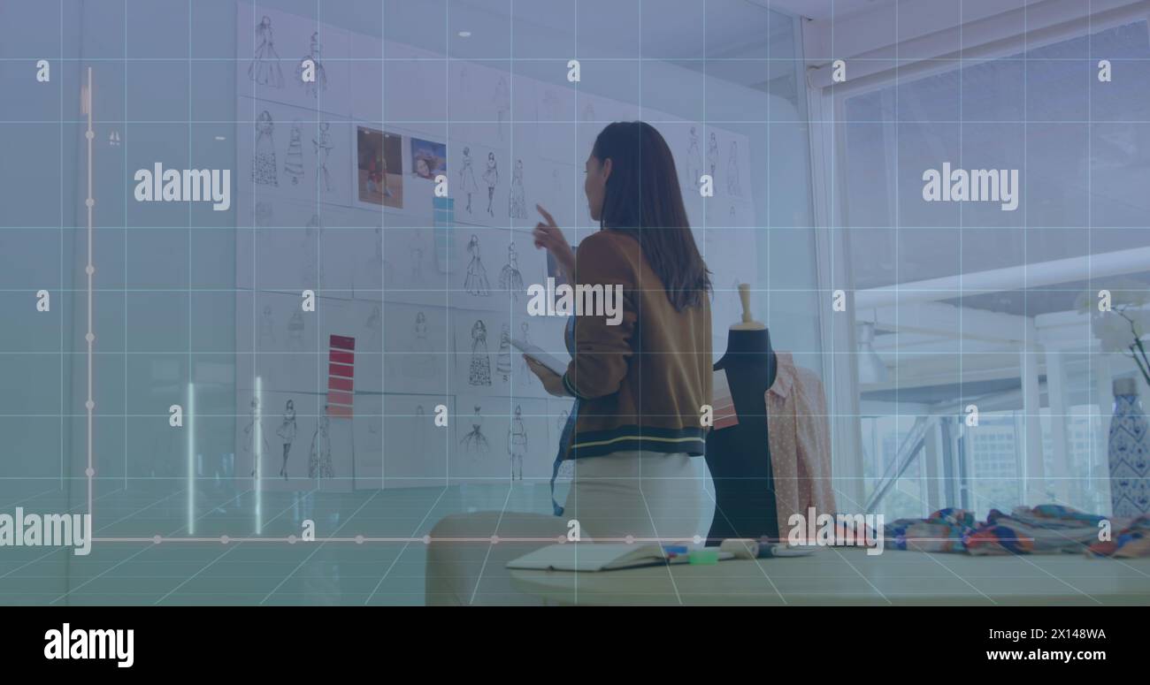 Image du langage informatique et graphique sur le concepteur féminin biracial vérifiant la conception de la robe Banque D'Images