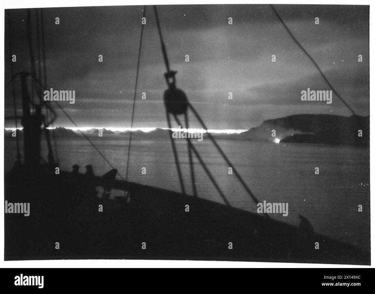 Pendant le raid du Spitzberg, le soleil de minuit illumine une décharge de charbon en feu, mettant en évidence les conditions opérationnelles et environnementales. Banque D'Images