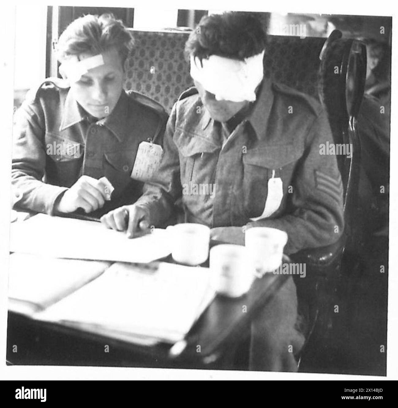 Un soldat britannique blessé lit et traduit la nouvelle à un commando français blessé à son retour chez lui. Banque D'Images