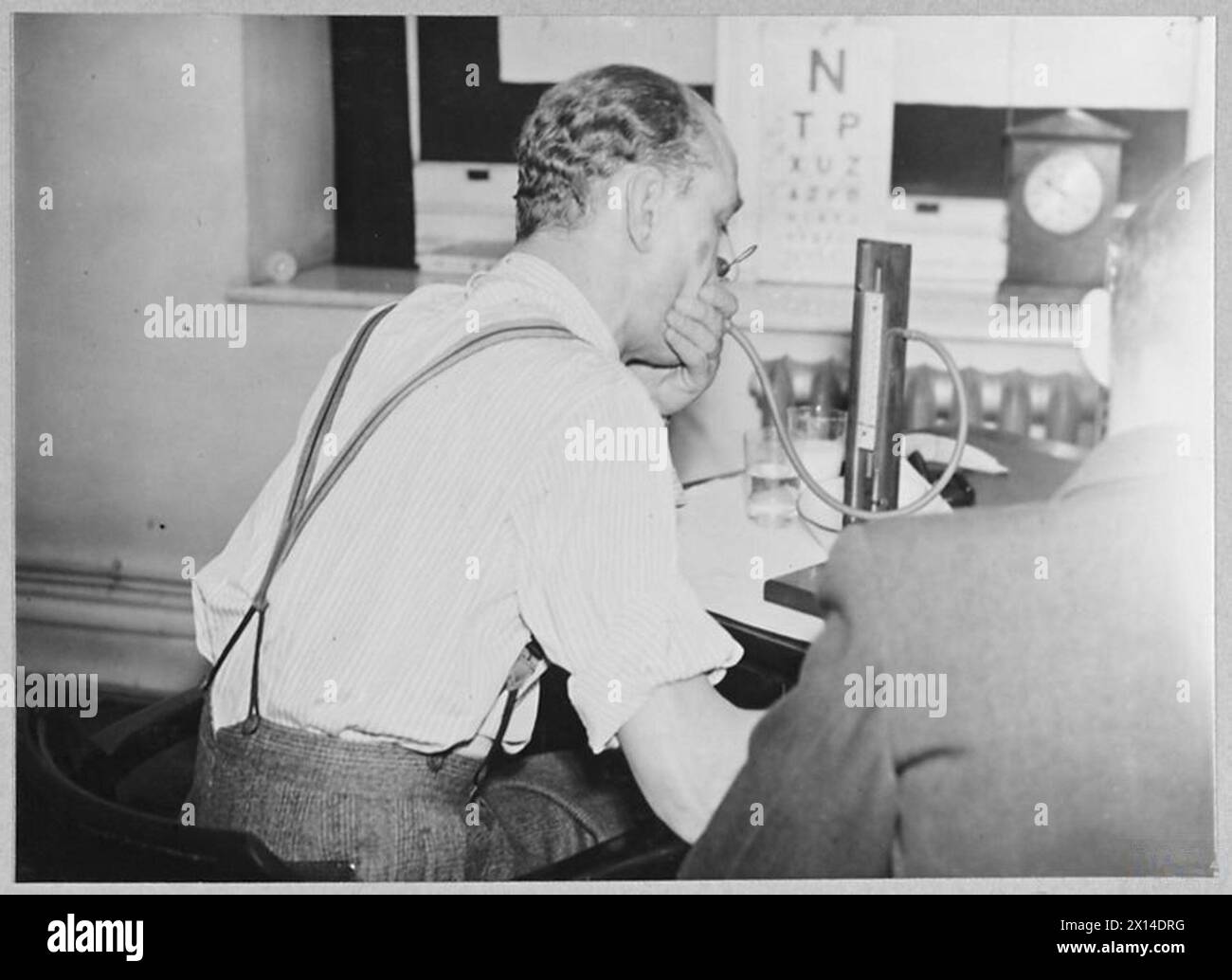 Candidat réalisant le test de capacité pulmonaire de quarante millimètres à l'aide d'un instrument de mesure du mercure, avec surveillance du pouls, pour évaluer l'adéquation pour les équipages de la Royal Air Force. Banque D'Images