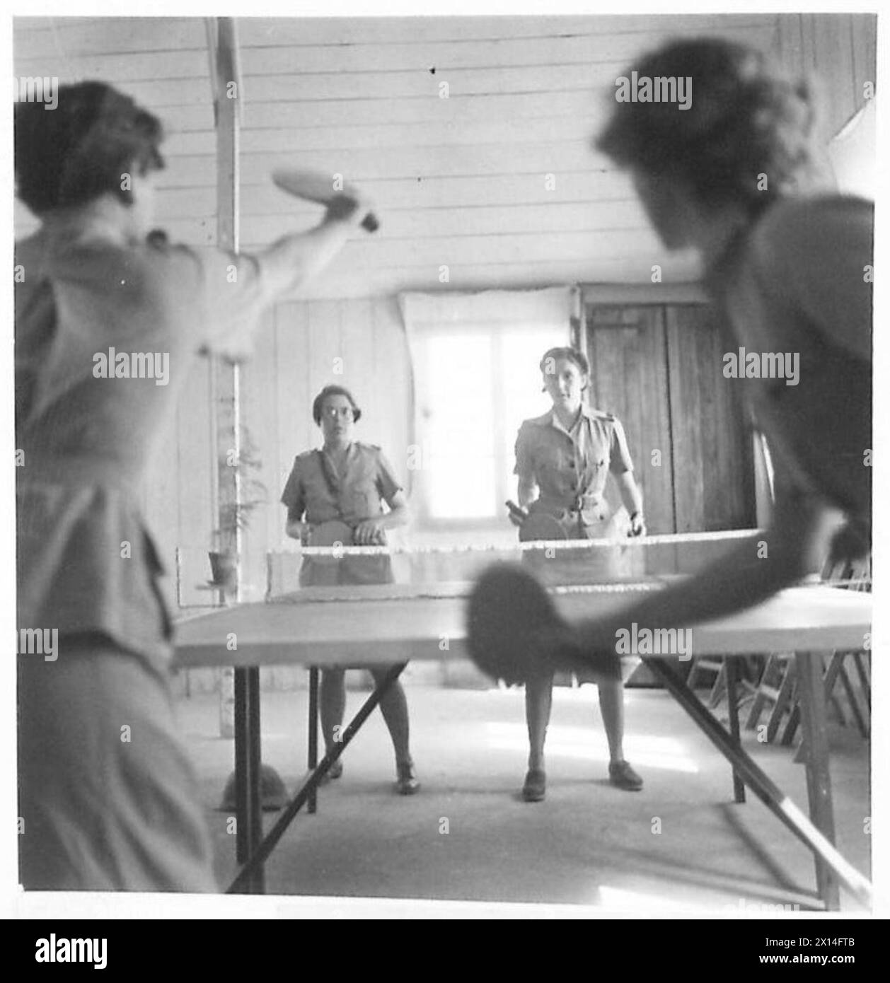 Les femmes servant dans les services auxiliaires de l'armée jouent au tennis de table dans un camp du désert, faisant preuve d'activités récréatives et de camaraderie parmi le personnel militaire. Banque D'Images