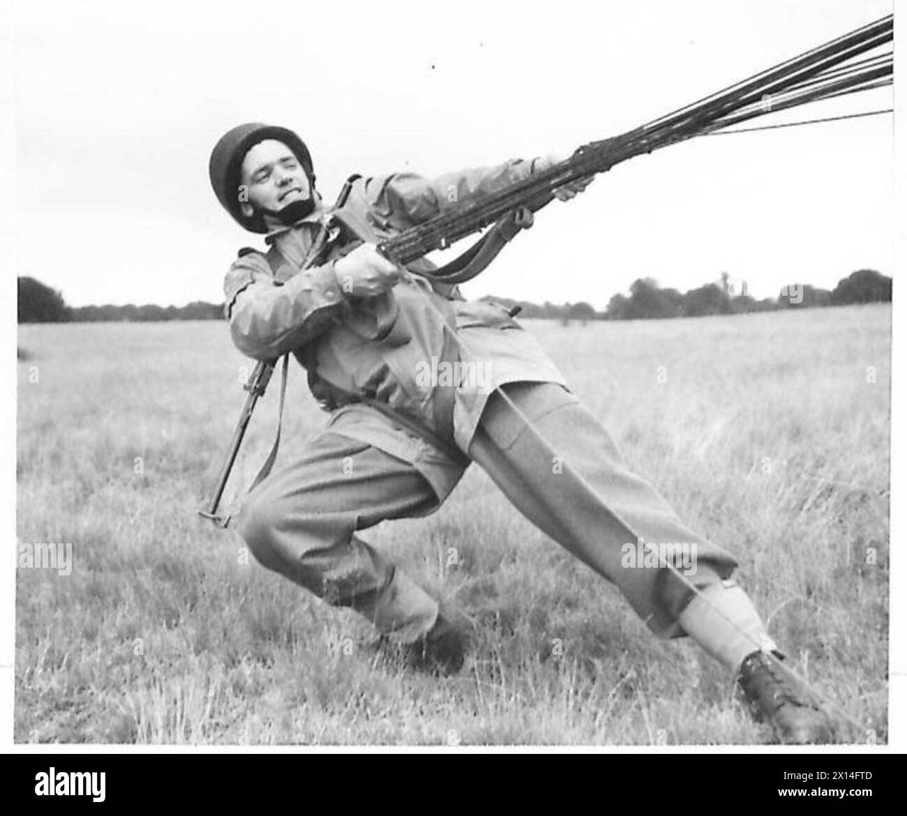 Un parachutiste de l'armée britannique tire les lignes de son parachute après l'atterrissage pour le dégonfler et se préparer à une action immédiate pendant l'entraînement. Banque D'Images