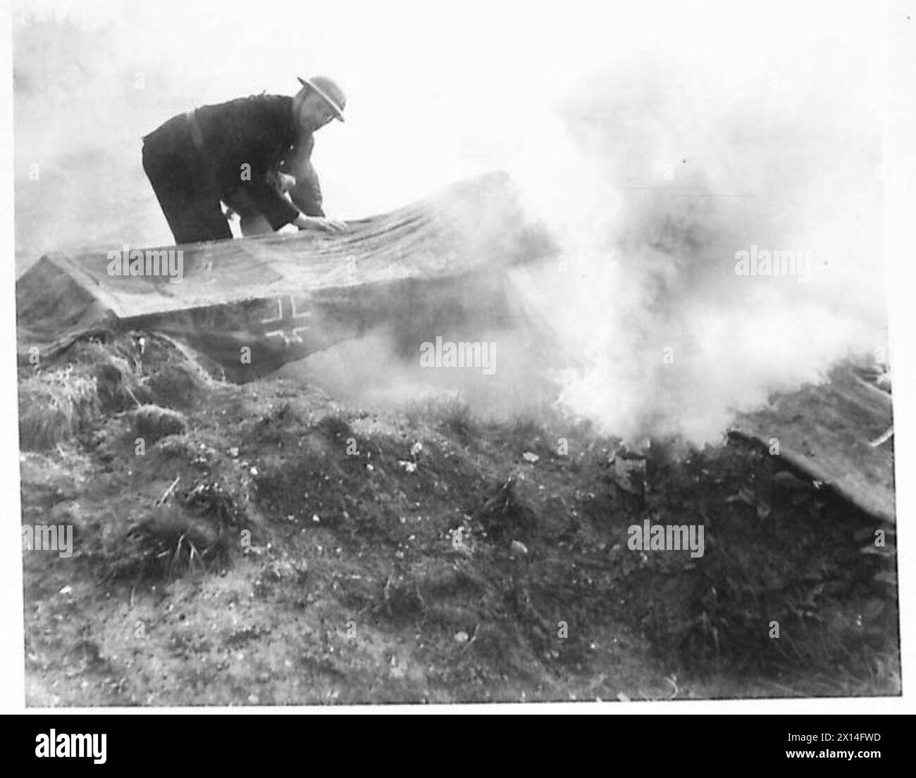 Des agents de la protection civile inspectent l'épave en feu d'un avion allemand mannequin en toile au cours d'un exercice d'invasion à grande échelle du Southern Command. Banque D'Images Des agents de la protection civile inspectent l'épave en feu d'un avion allemand mannequin en toile au cours d'un exercice d'invasion à grande échelle du Southern Command. Banque D'Images