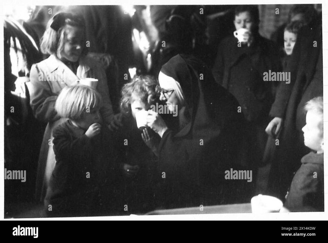Une religieuse apporte du réconfort et de la nourriture aux enfants hollandais évacués des zones de bataille, illustrant les soins humanitaires pendant les opérations militaires. Banque D'Images