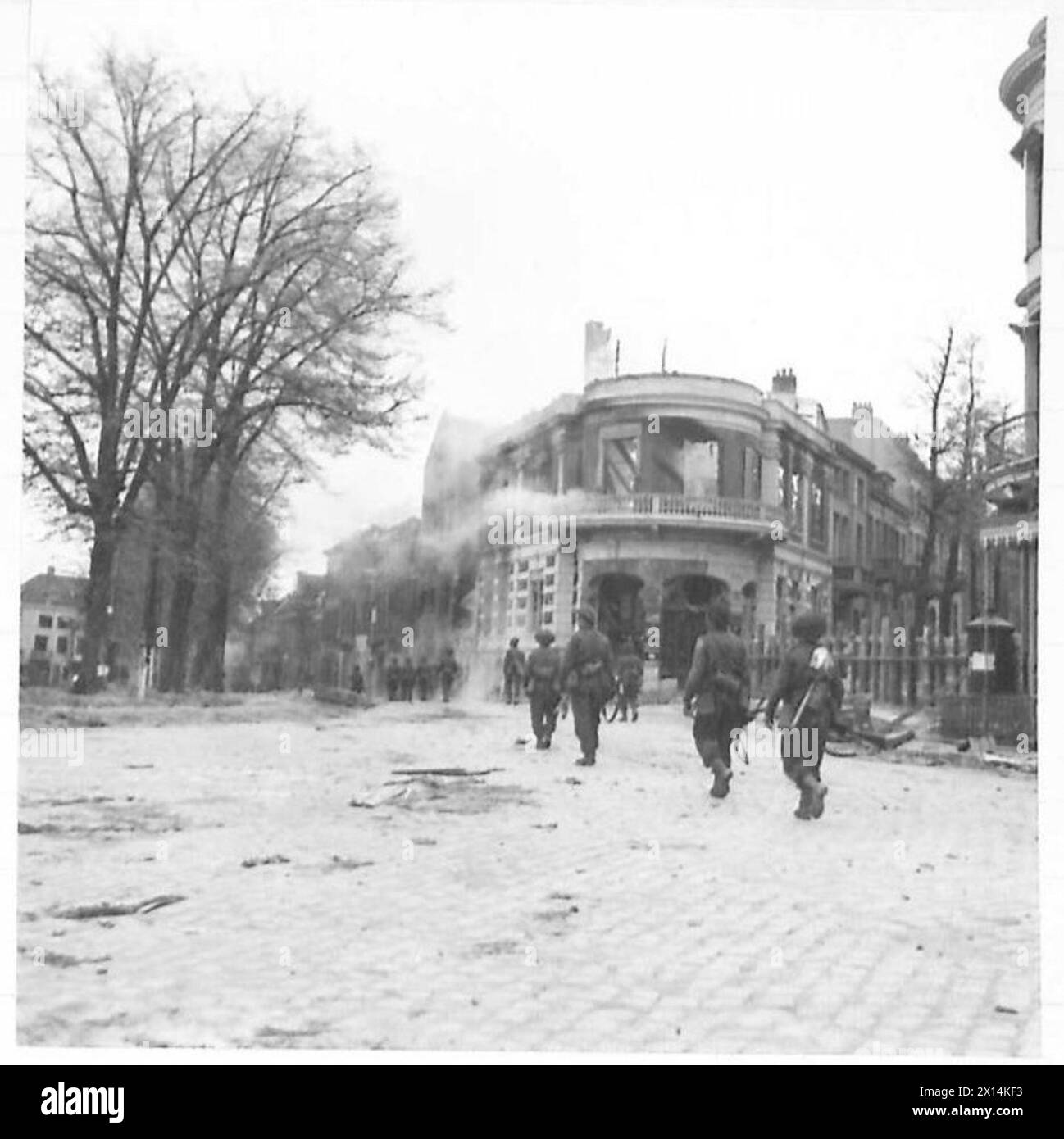 Les troupes britanniques marchent dans les rues d'Arnhem, passant devant plusieurs bâtiments incendiés lors des opérations de combat urbain dans la ville. Banque D'Images