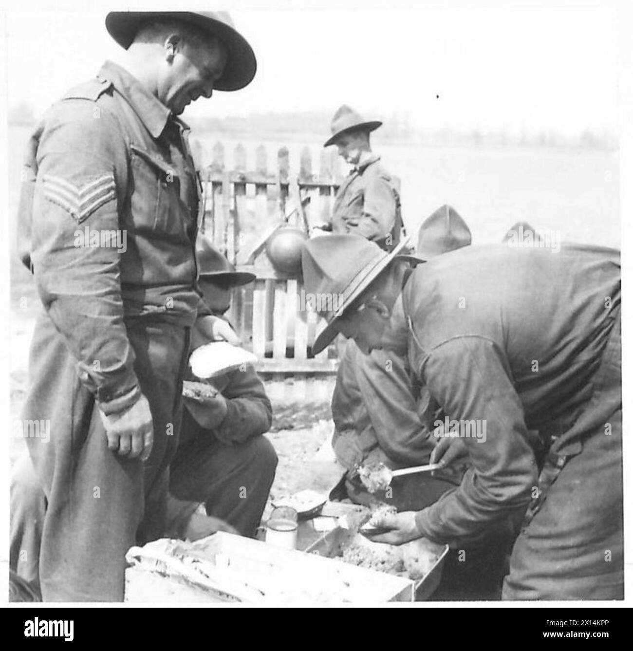 Les bushmen néo-zélandais servent de la nourriture au personnel lors du repas de mi-journée, démontrant les routines de subsistance sur le terrain et le travail d'équipe. Banque D'Images