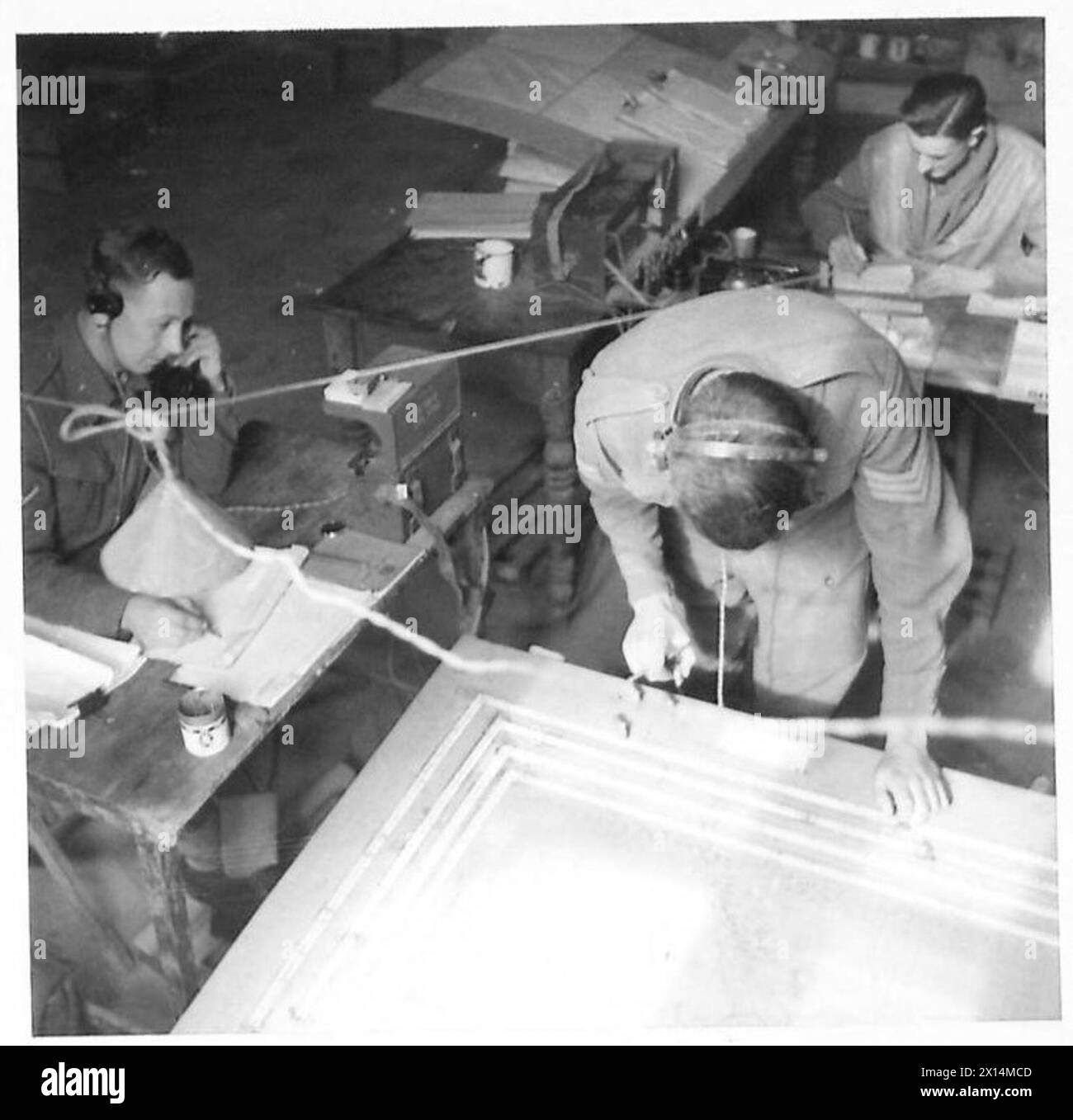 Dans le centre de traçage d'Une troupe, 55 batterie d'observation, 8th Surrey Regiment, R.A. téléphone l/Bdr. Bodger enregistre les rapports de quatre postes de repérage. Le Sgt. I.D. Matthews les trace sur un tableau de concentration en utilisant quatre marqueurs représentant chaque ligne de visée. L'armée britannique coordonne le ciblage de l'artillerie par l'observation et le complot. Banque D'Images Dans le centre de traçage d'Une troupe, 55 batterie d'observation, 8th Surrey Regiment, R.A. téléphone l/Bdr. Bodger enregistre les rapports de quatre postes de repérage. Le Sgt. I.D. Matthews les trace sur un tableau de concentration en utilisant quatre marqueurs représentant chaque ligne de visée. L'armée britannique coordonne le ciblage de l'artillerie par l'observation et le complot. Banque D'Images