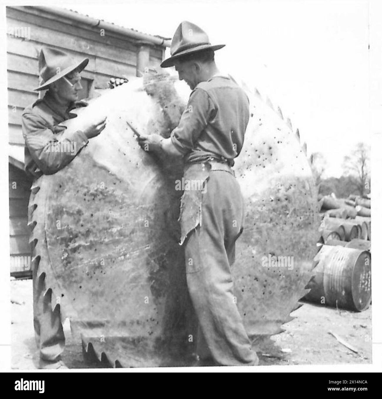 Les bushmen néo-zélandais travaillent dans une scierie, avec un scieur qui teste la grande scie circulaire pour la tension. Banque D'Images