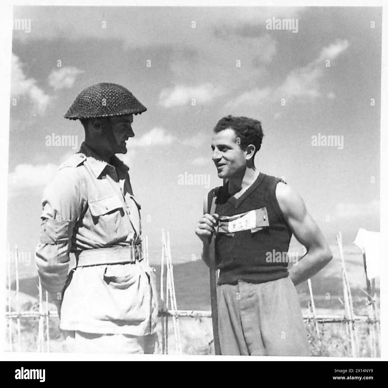 Le Cpl E. Ewart de la section de la sécurité sur le terrain de 31 s'entretient avec Borga Giovanni, un partisan italien de Montefiore affichant l'insigne F.L.N. de l'armée britannique, de la huitième armée. Banque D'Images