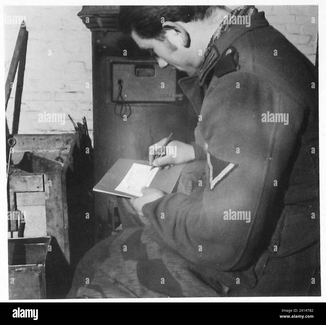 Un prisonnier de guerre écrit une carte de la Croix-Rouge à sa famille peu après son arrivée au camp, sous la supervision de l'armée britannique. Banque D'Images