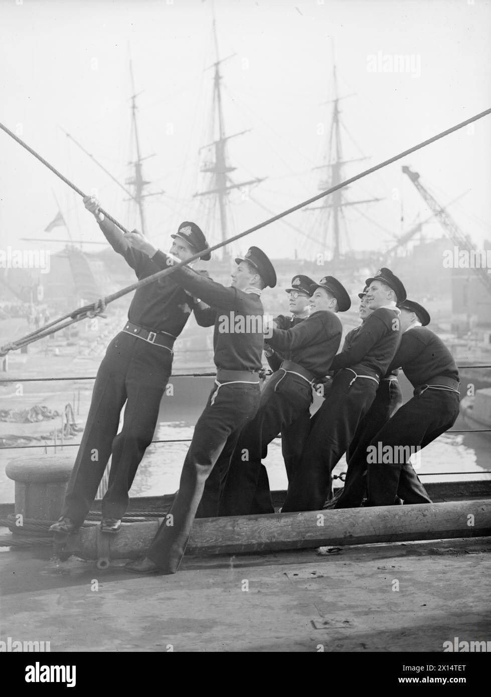 LE NAVIRE DE FORMATION DES CADETS HMS FROBISHER PART POUR UNE CROISIÈRE D'HIVER. LE 4 JANVIER 1946, À BORD DU HMS FROBISHER À PORTSMOUTH. LE NAVIRE D'ENTRAÎNEMENT PART POUR UNE CROISIÈRE D'HIVER DE TROIS MOIS VERS LES ANTILLES. AVANT DE QUITTER PORTSMOUTH, ILS SONT INSPECTÉS PAR LE COMMANDANT EN CHEF, L'AMIRAL SIR GEOFFREY LAYTON. - Hull Away! Ces cadets de la Royal Naval travaillent avec un testament alors qu'ils se préparent au départ. En arrière-plan, LA VICTOIRE de Nelson sur le HMS Banque D'Images