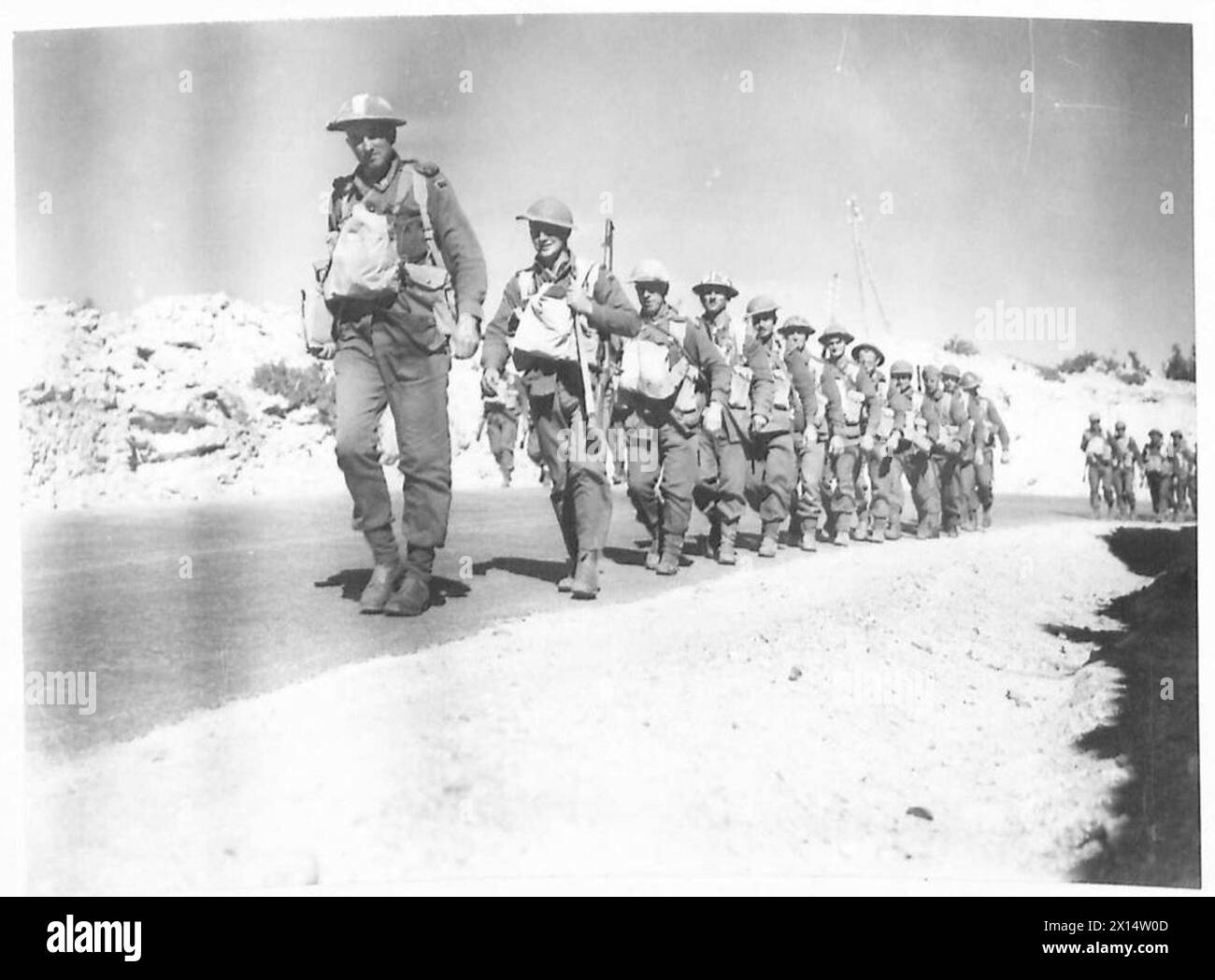 Photographies montrant des hommes de l'armée britannique et du matériel sur la route vers l'avant près de Derna, marchant à travers un pays vert sur de bonnes routes Banque D'Images