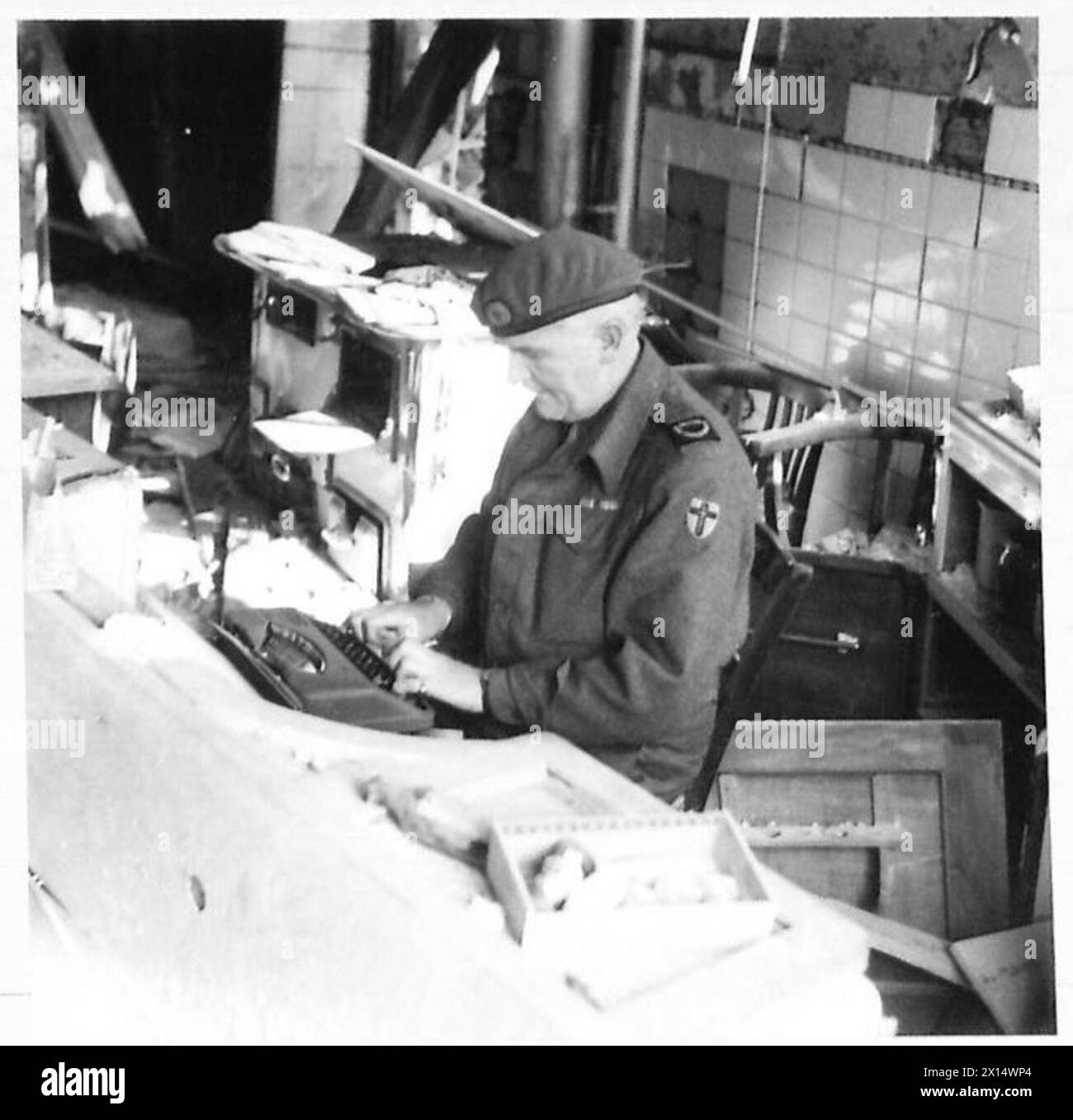 Le correspondant de guerre James McDonald types dépêche depuis l'Allemagne dans les ruines d'une maison lors des opérations de l'armée britannique dans le Nord-Ouest de l'Europe. Banque D'Images