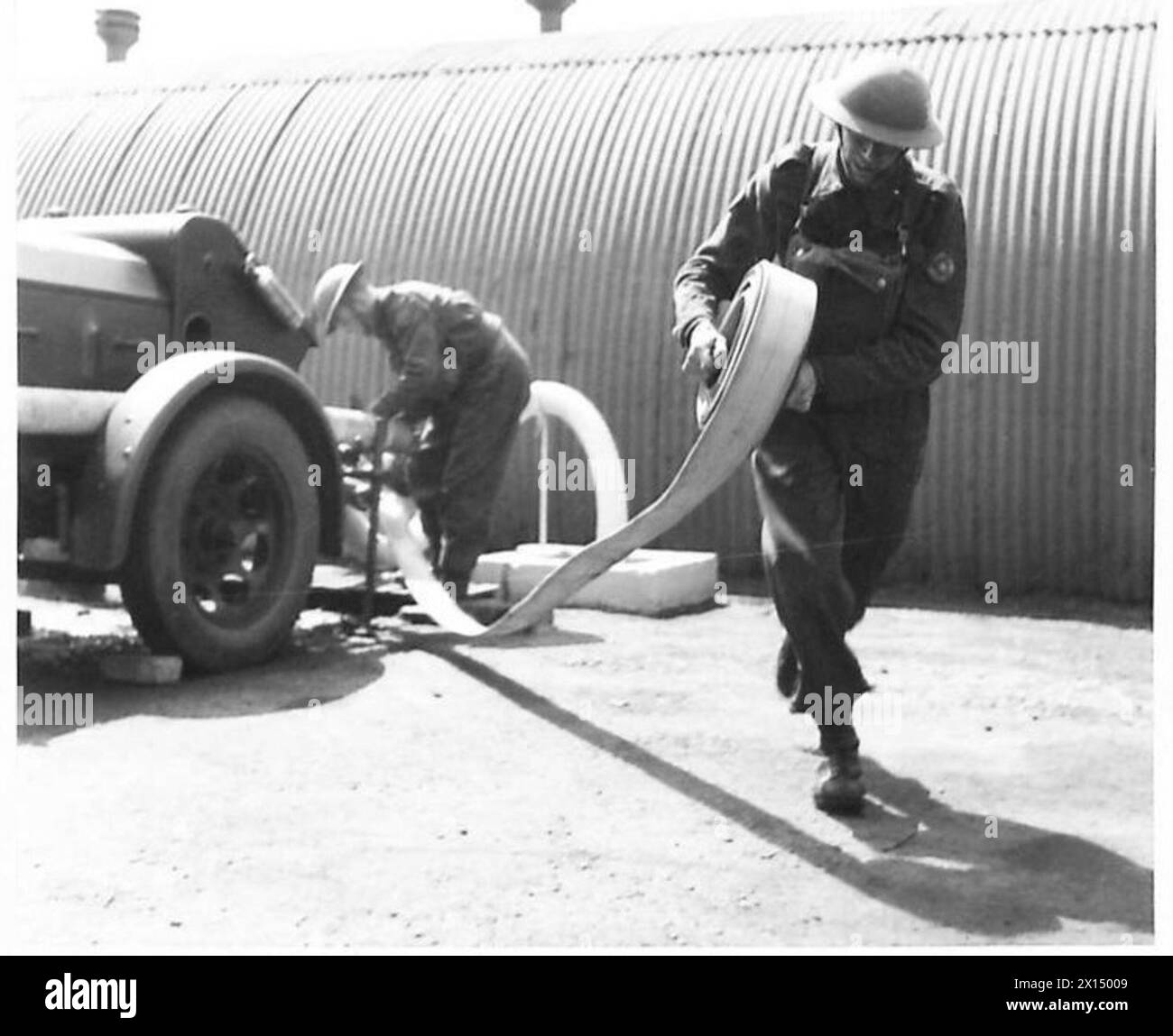 Les pompiers de l'armée actionnent une pompe de remorque, positionnent le tuyau d'aspiration dans une source d'eau statique et préparent le moteur à réagir à un incendie. Banque D'Images