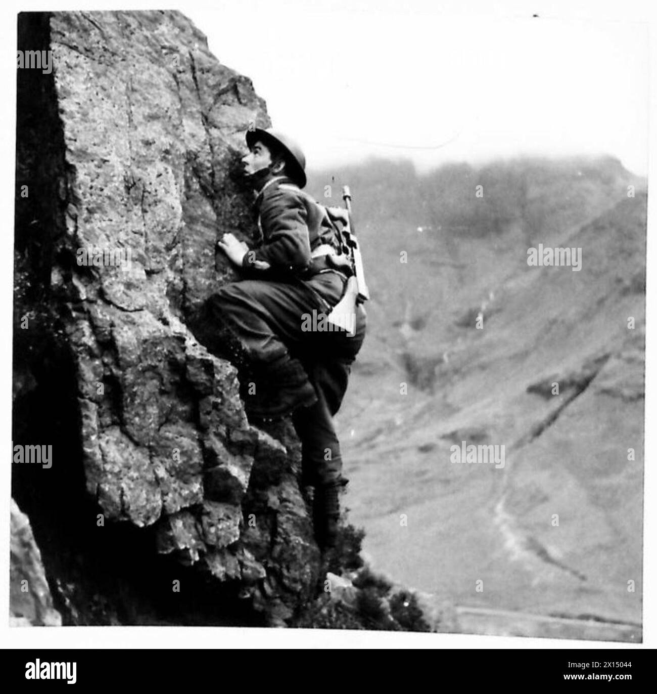 Un commando de l'armée britannique en formation grimpe une structure tout en portant un fusil Tommy, démontrant sa préparation physique et la manipulation des armes à feu. Banque D'Images