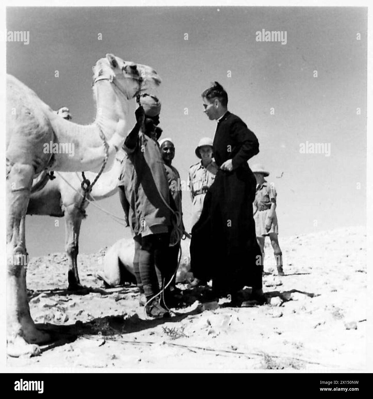 Le Padre interagit avec les chauffeurs de chameaux après avoir conduit un défilé dans l'église dans le désert pour le personnel de l'armée britannique. Banque D'Images