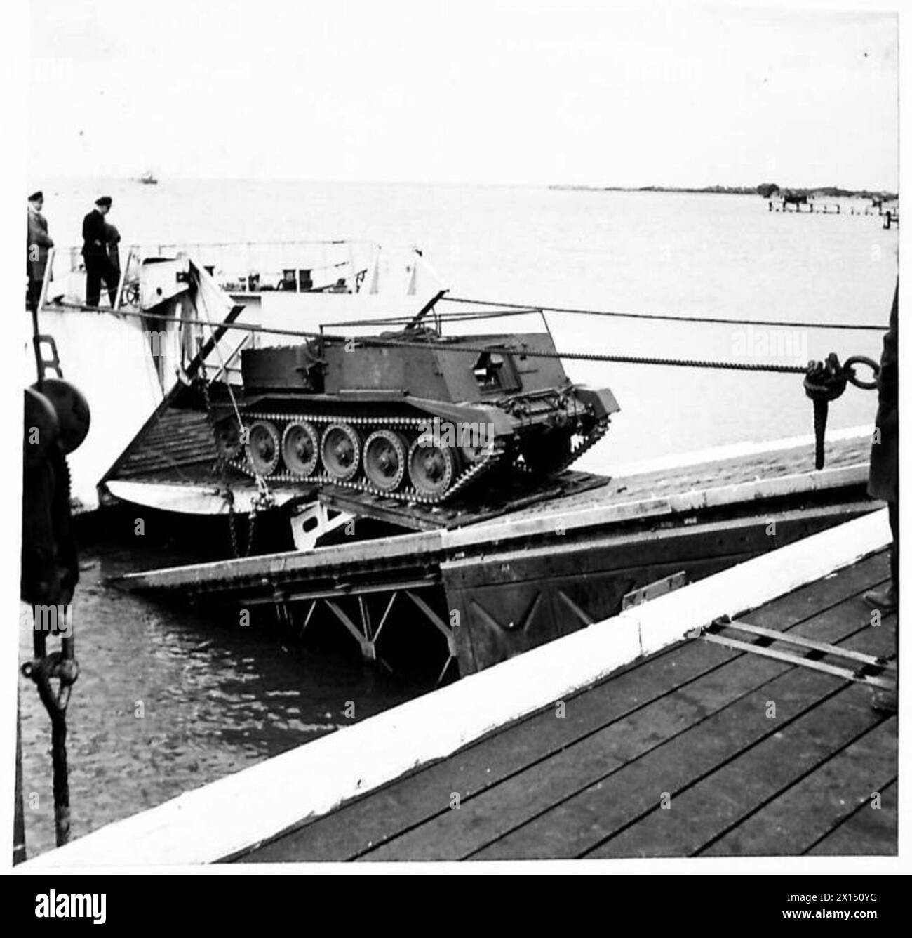Les véhicules et les équipements blindés sont chargés et déchargés entre une jetée composite et un réservoir de débarquement (L.C.T.), soutenant les opérations de transport militaire. Banque D'Images