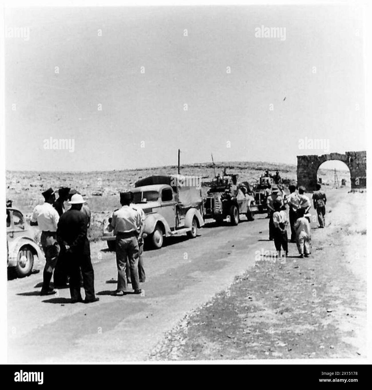 Des habitants et des officiers français observent des camions et des véhicules blindés britanniques sur une route près de la frontière turque pendant l'occupation de la Syrie. Banque D'Images