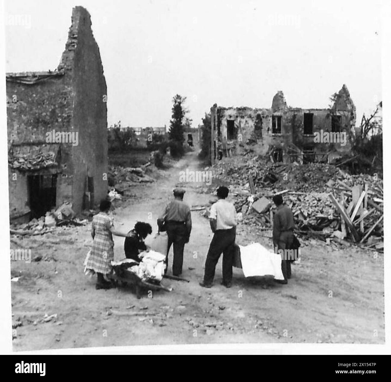 Une FAMILLE FRANÇAISE RETOURNE À LEUR VILLAGE DÉCHIRÉ D'OBUS - comme ils arrivent dans le village, ils voient pour la première fois la rue du village British Army, 21st Army Group Banque D'Images