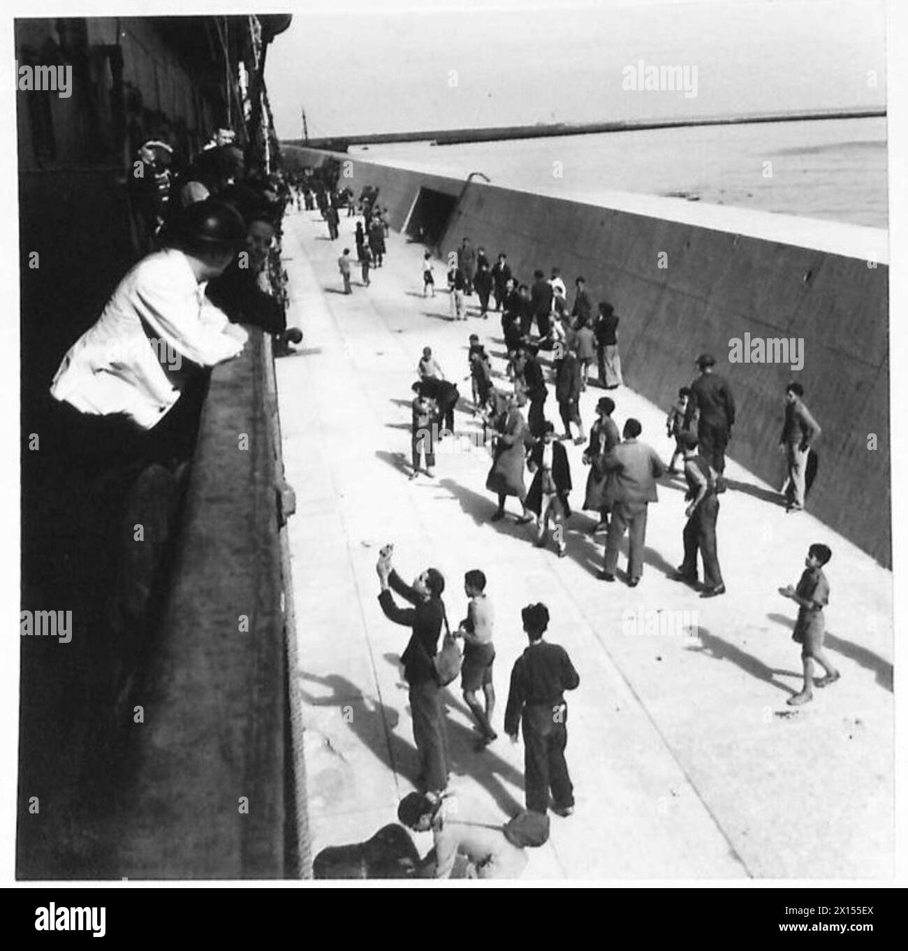 Les garçons arabes collectent les pièces de monnaie et les cigarettes lancées par les troupes de la Royal Navy à partir d'un navire de troupes entrant dans le port d'Alger le 9 novembre 1942 lors de l'opération Torch. Banque D'Images