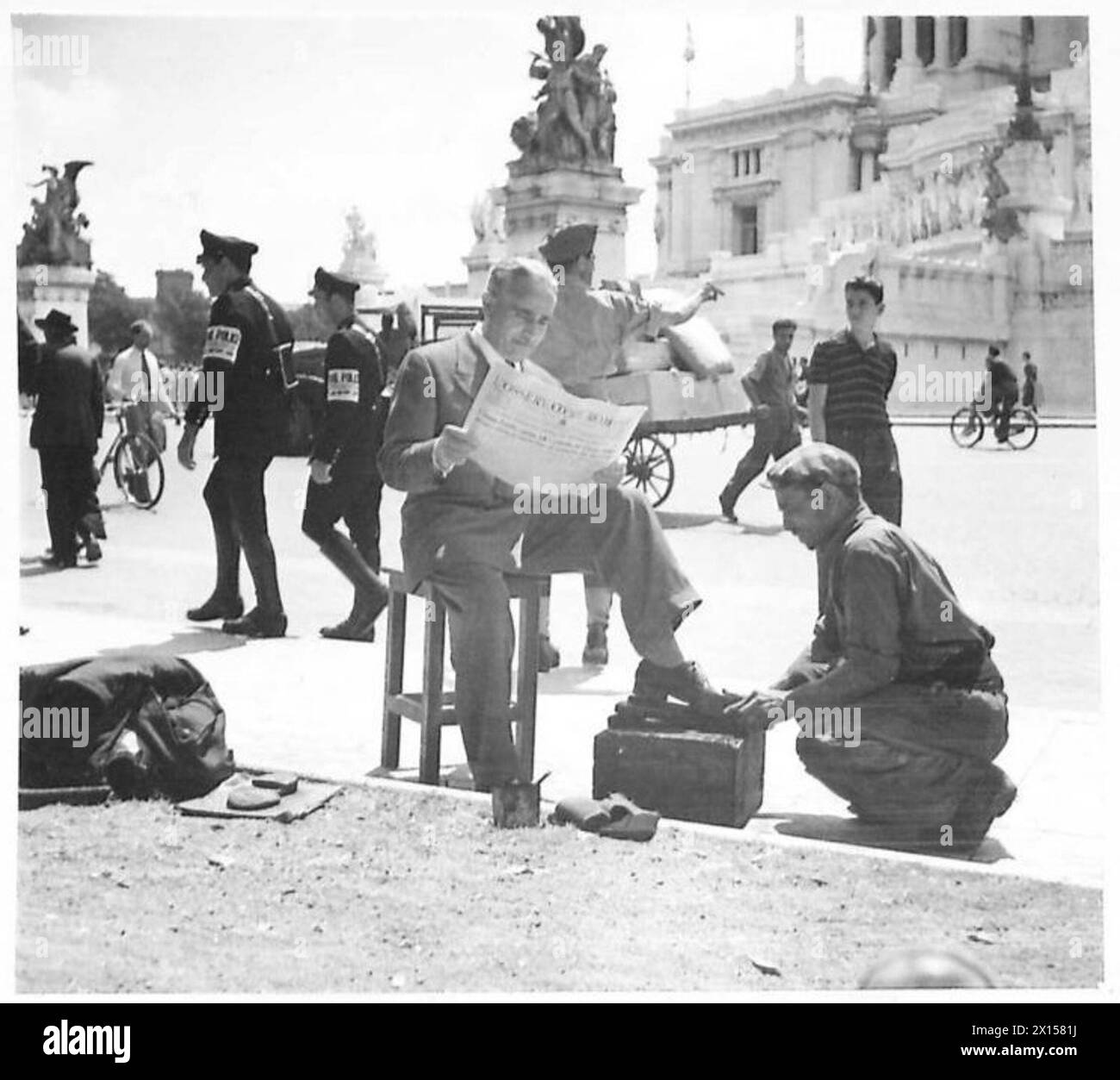 Le personnel de l'armée britannique lit les nouvelles à divers endroits, y compris en recevant des chaussures brillantes, avec le mémorial Victor Emmanuel II visible en arrière-plan. Banque D'Images