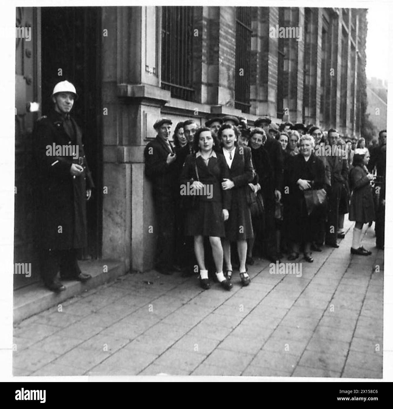 Des civils belges font la queue devant une banque pour échanger de l'argent émis par l'Allemagne contre de nouveaux billets dans le cadre de la réglementation financière post-libération pour prévenir l'inflation, British Army, 21st Army Group. Banque D'Images
