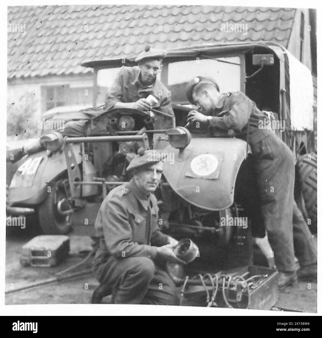 Trois hommes de la R.A.S.C.—Ptes. F. Furlong, A.H. Sewell et A. Lamb—travaillent sur un véhicule tandis que le capitaine McIntosh, officier observateur, documente des illustrations pour des histoires dans la 15e division écossaise de l'armée britannique, 21e groupe d'armées. Banque D'Images