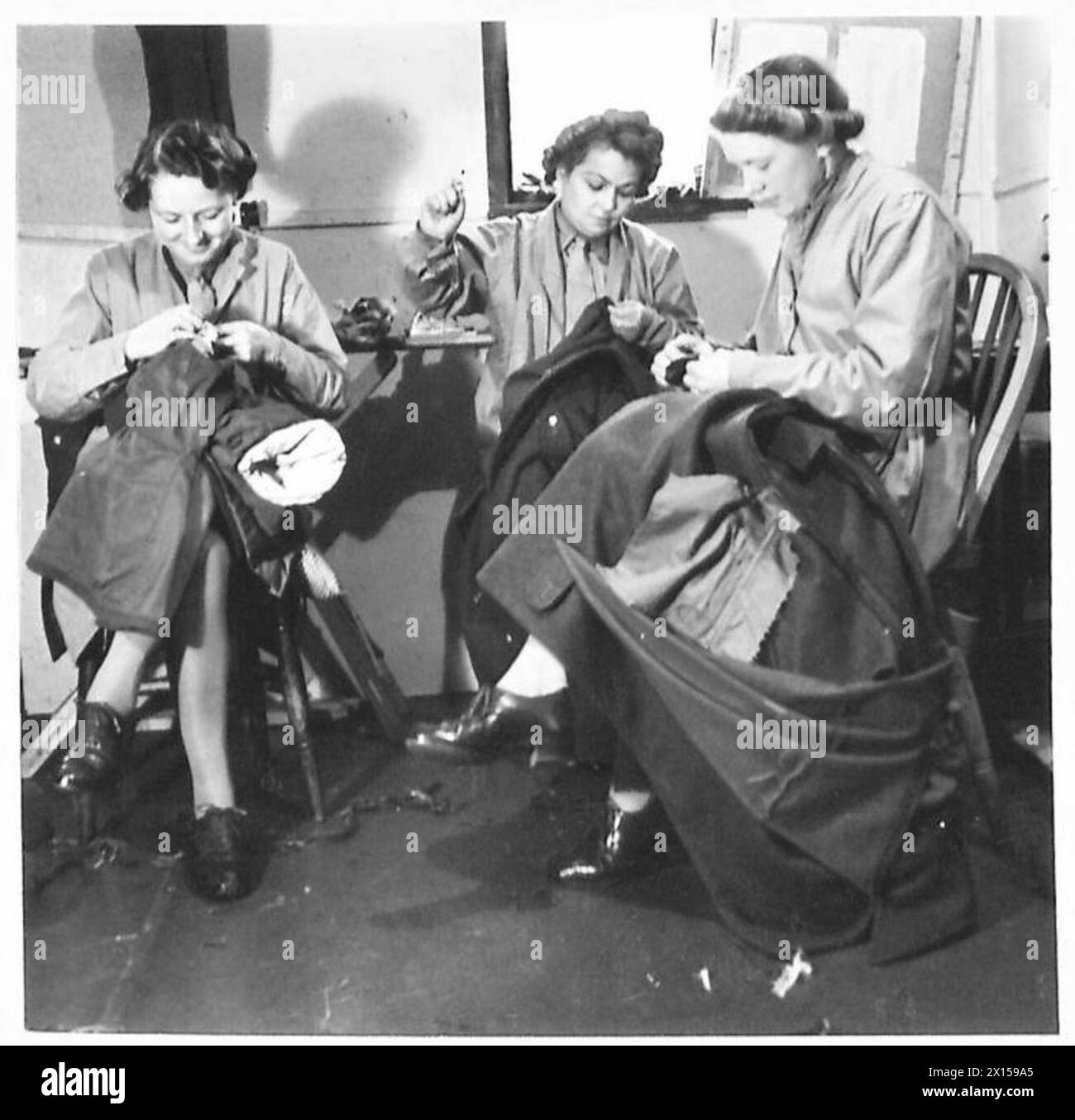Les soldats E.M. Radford, M.E. Raine et H.R. Lerov-Laidlaw travaillent dans l’atelier du tailleur, effectuant l’entretien et la réparation des uniformes. Banque D'Images