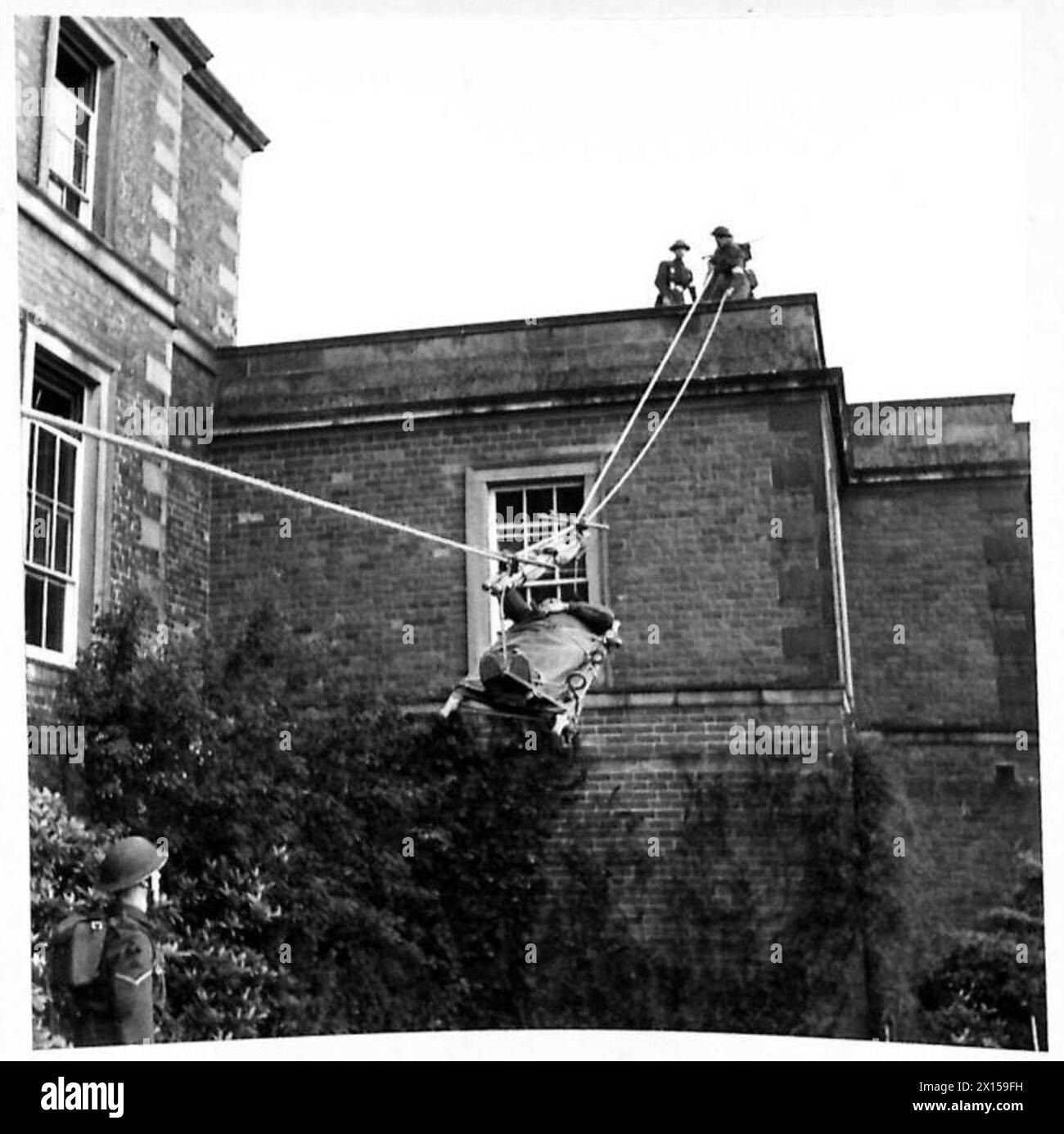 Des correspondants de guerre écossais observèrent le personnel du Royal Army Medical corps descendre une civière d'un bâtiment pendant des opérations d'ambulance. Banque D'Images