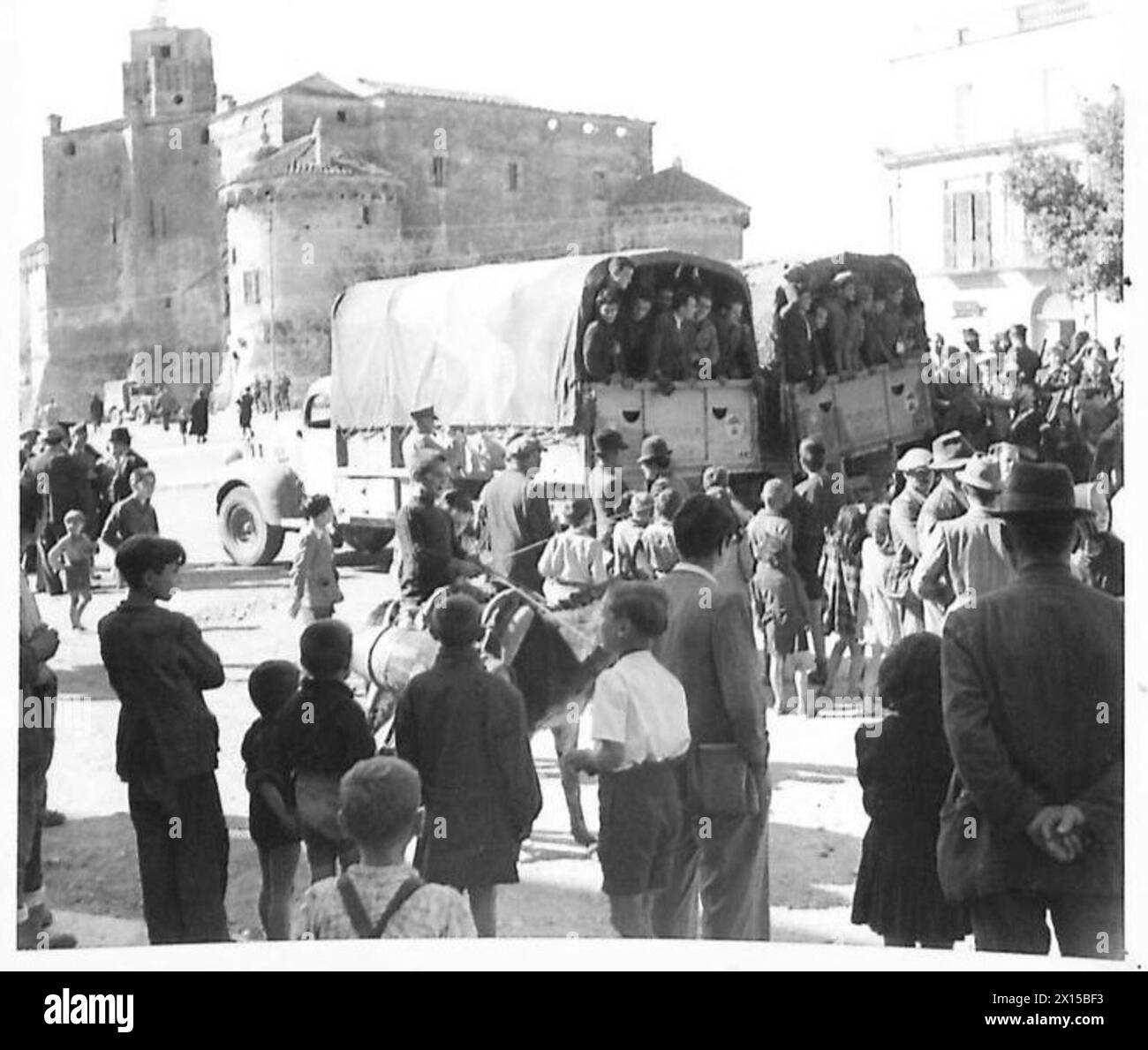 En Italie, les troupes italiennes sont rappelées au service alors que des camions chargés attendent sur la place de la ville, avec le vieux château visible en arrière-plan, British Army. Banque D'Images