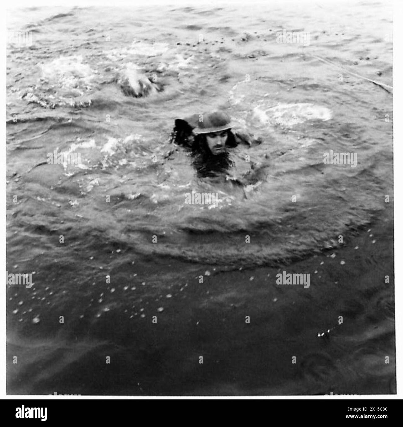 Un nageur transporte un câble métallique de l'autre côté de la rivière pour aider à transporter les victimes vers la rive opposée lors d'une opération de l'armée britannique. Banque D'Images
