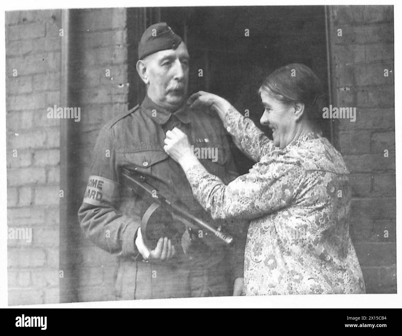 Un sergent de la Home Guard s'arme d'un fusil Tommy et prépare l'équipement avant le service, illustrant la préparation de la défense nationale pour l'armée britannique. Banque D'Images