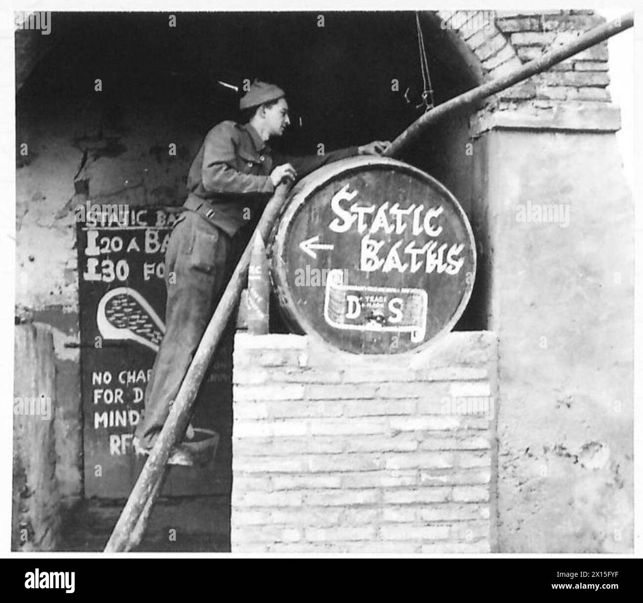 L'ARMÉE BRITANNIQUE EN AFRIQUE DU NORD, EN SICILE, EN ITALIE, DANS LES BALKANS ET EN AUTRICHE 1942-1946 - RFN. F. Saunders de 86 Westfield Avenue, Watford, Herts regarde le baril qui est rempli à partir du pipeline aérien menant de la pompe dans la cour de l'armée britannique Banque D'Images