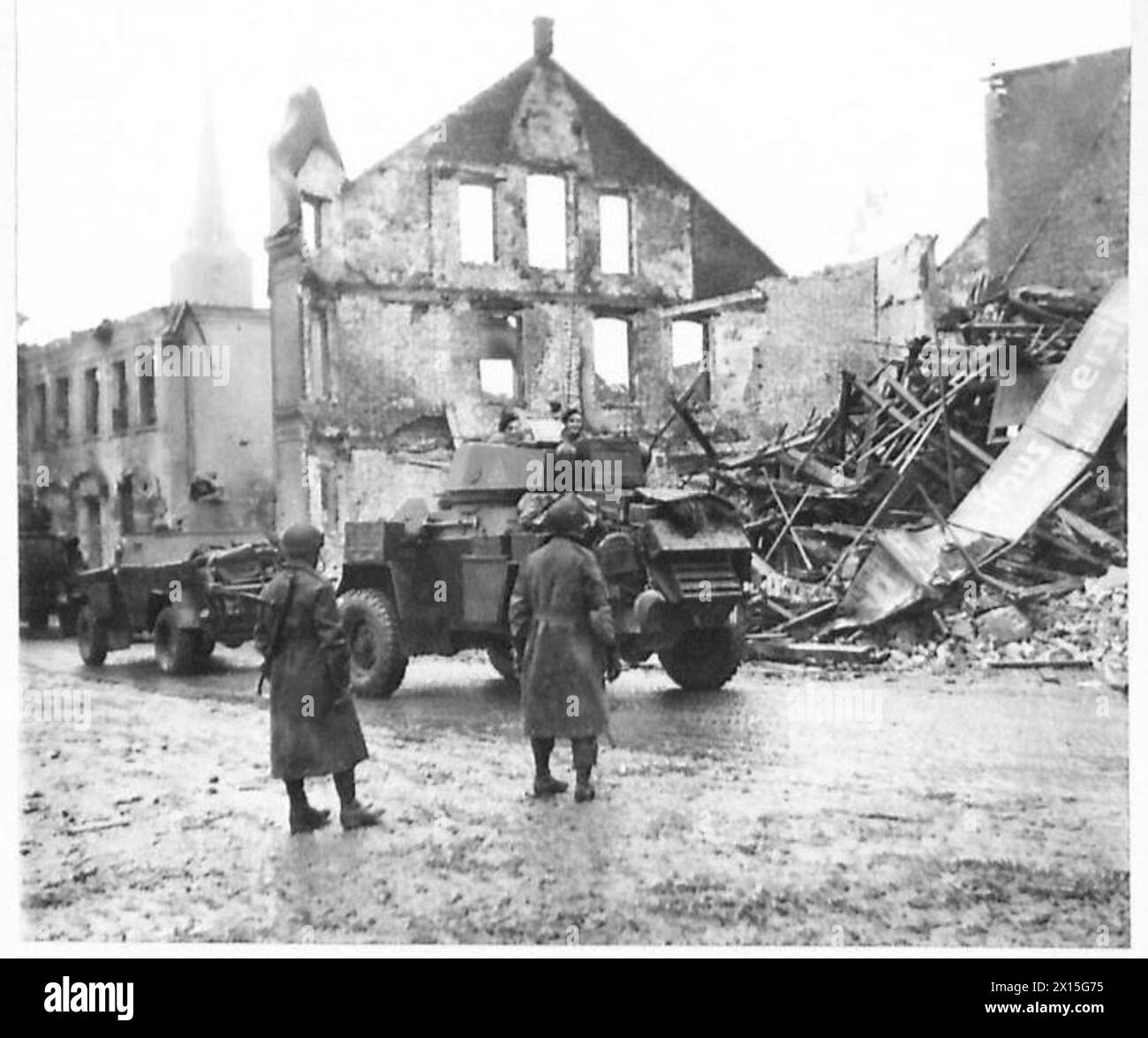 Des unités blindées avancent à travers Geldern pendant les opérations de l'armée britannique, démontrant le mouvement et la coordination des chars et du personnel. Banque D'Images