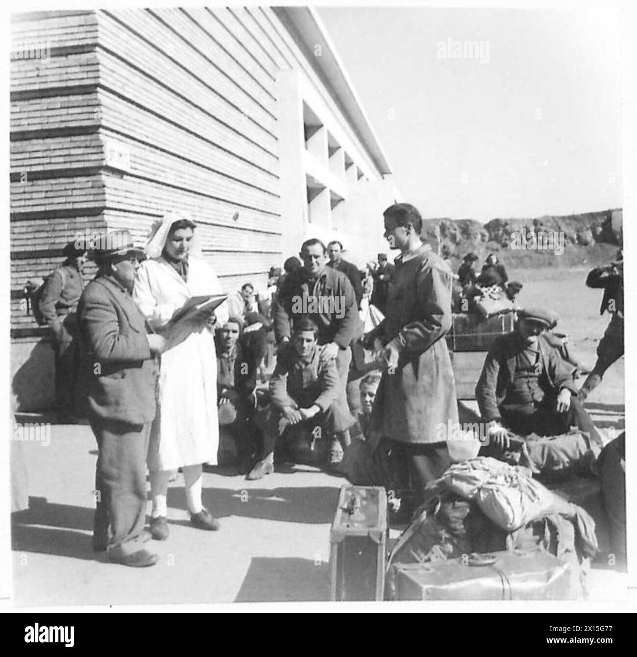Les réfugiés arrivant en train de Florence sont individuellement enregistrés et décapés dans les bâtiments de la gare avant de se reposer sur leurs bagages en attendant leur transfert vers un camp de réfugiés en Italie. Banque D'Images