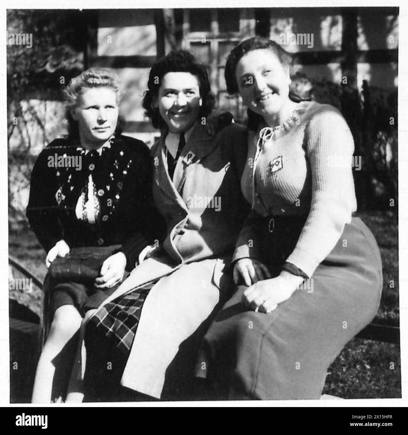 Trois filles polonaises, anciennement travailleuses forcées en Allemagne, sourient après la libération, portant des insignes marqués « P » qui identifiaient leur nationalité pendant l'occupation nazie. Banque D'Images