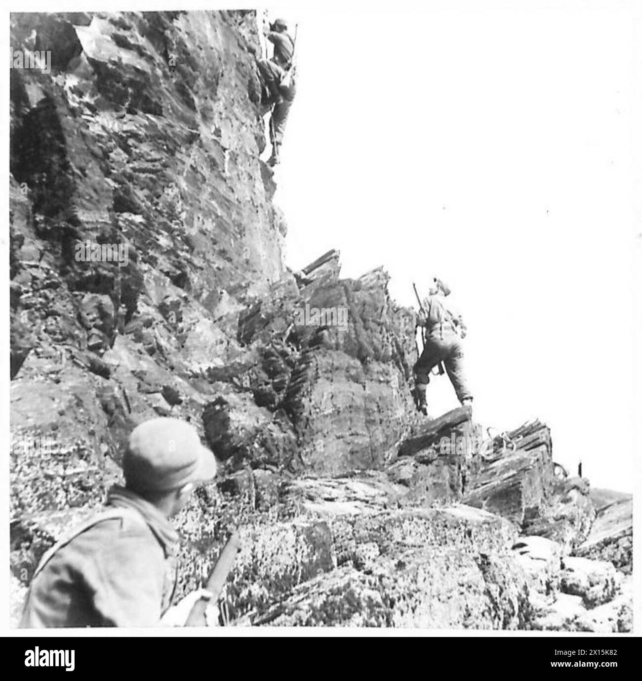 Photographie montrant des membres des « Devils verts » qui se préparent à gravir une falaise perpendiculaire pendant les exercices d'entraînement de l'armée britannique. Banque D'Images