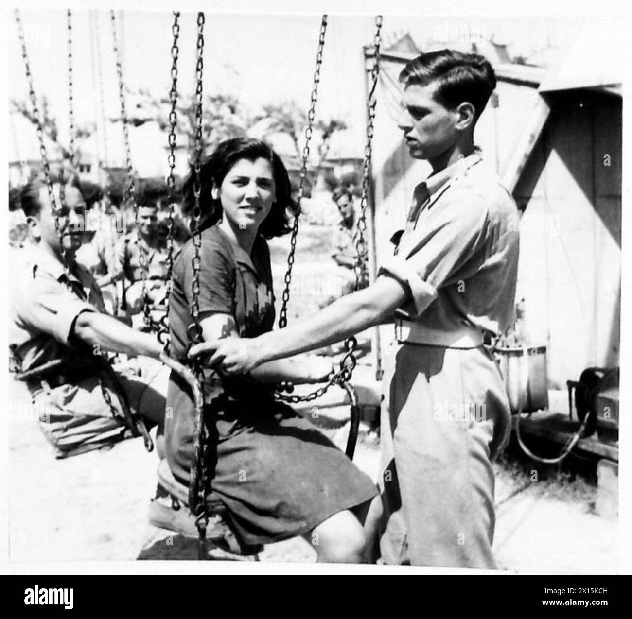 Le sergent William G. Firman gère une foire funéraire, des salles de spectacle et des cinémas pour les troupes d'outre-mer au camp de repos de Grado, ajustant la chaîne de sécurité chair-o-plane. Banque D'Images