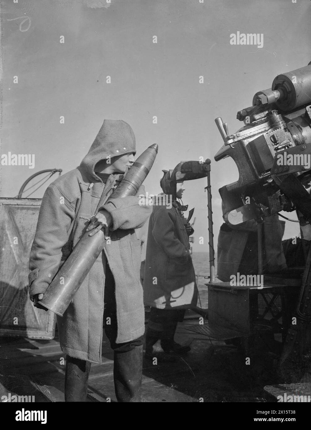 DIVERSES SCÈNES À BORD DU DESTROYER HMS KELVIN. 1940. - Un baiser humoristique pour la chance est donné à un obus par un artilleur sur le point de le placer dans un canon anti-aérien lors d'une attaque aérienne Banque D'Images