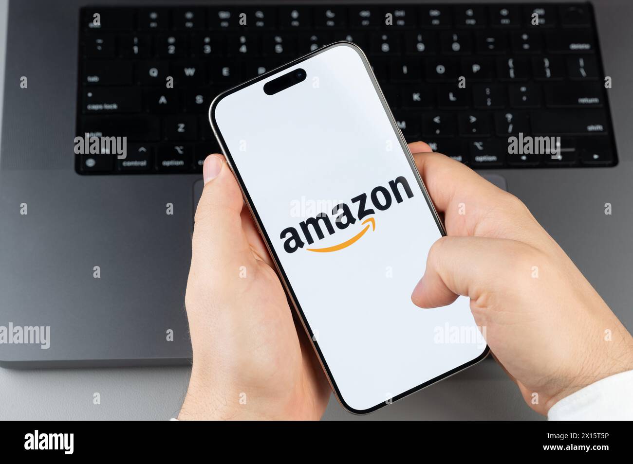 New York, États-Unis - 6 avril 2024 : populaire application mobile Amazon sur l'écran de smartphone dans les mains sur fond de clavier d'ordinateur portable Banque D'Images