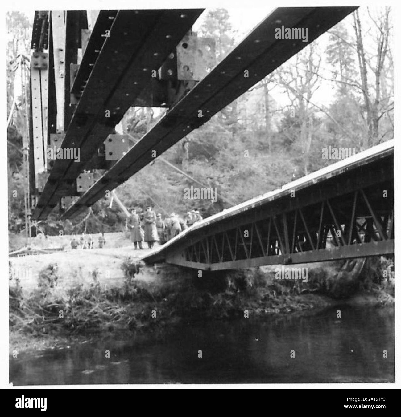 Les sections de pont sont transportées à travers une rivière tandis qu'un pont à poutres caissonnées précédemment érigé se trouve à droite, montrant les méthodes de construction et d'ingénierie. Banque D'Images
