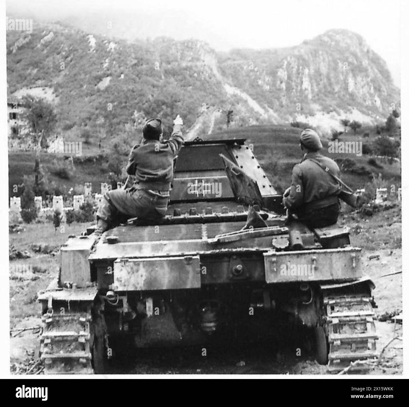 Un char allemand est montré détruit par la 6e division blindée, avec des soldats britanniques indiquant un terrain montagneux utilisé pour le positionnement stratégique. Banque D'Images