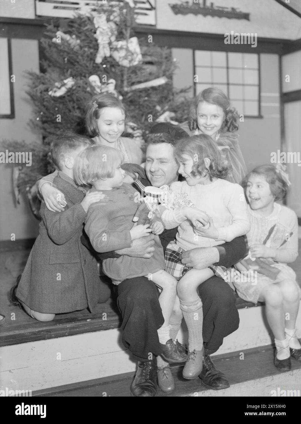 FÊTE DE VACANCES POUR LES ENFANTS DE MARINS. 31 DÉCEMBRE 1941, FLOTILLA CLUB, QUAI DE GLADSTONE, LIVERPOOL. - Un marin raconte une histoire aux enfants Banque D'Images