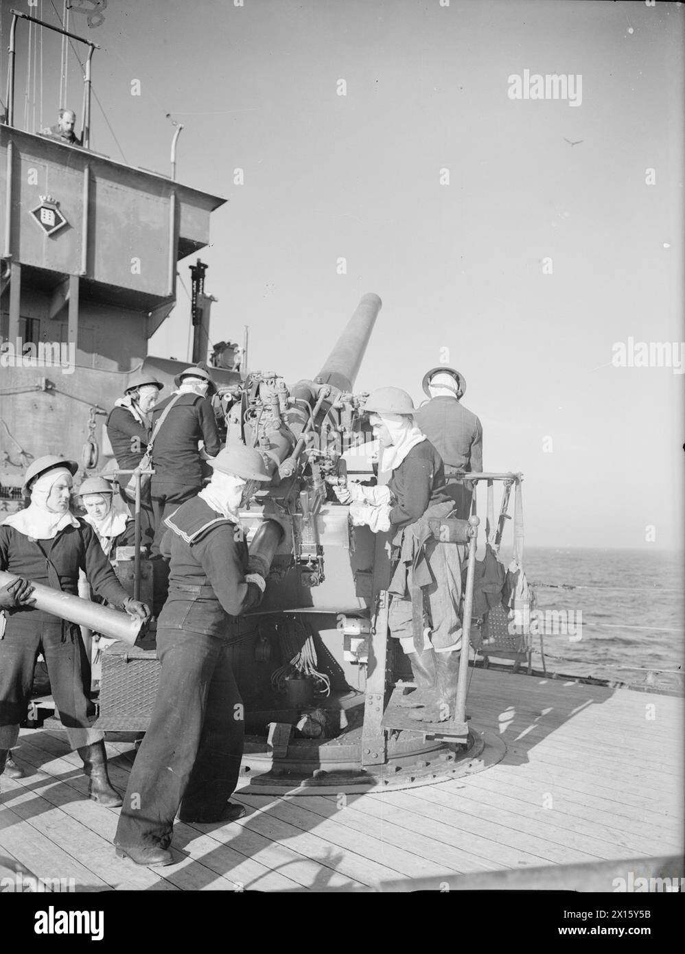 SCÈNES À BORD D'UN DRAGUEUR DE MINES. 1940, À BORD DU HMS HAZARD. - L'équipage de l'arme portant un casque anti-flash et des gants en amiante pour éviter les brûlures pendant le tir Banque D'Images