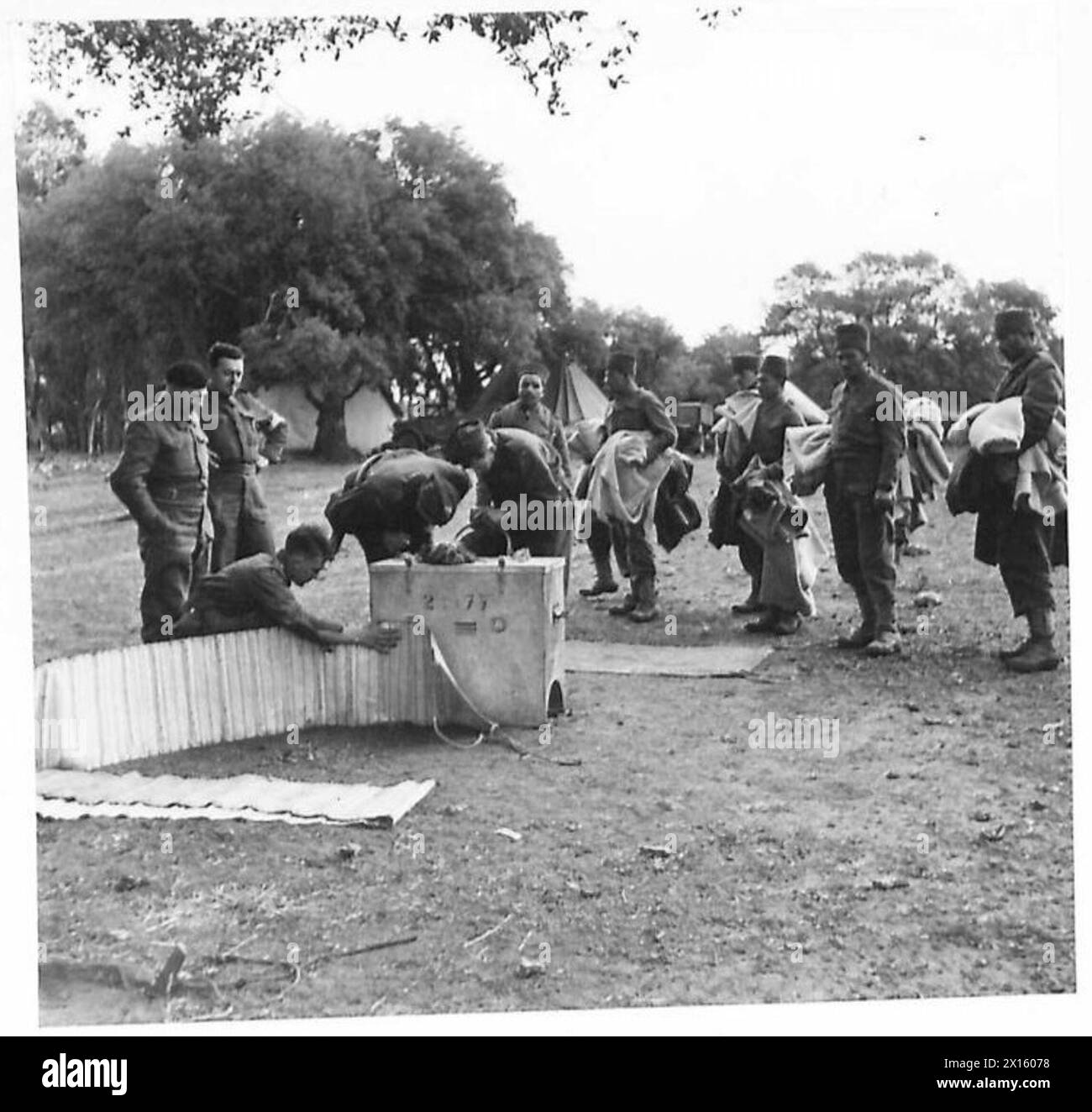 L'ARMÉE BRITANNIQUE DANS LA CAMPAGNE DE TUNISIE, NOVEMBRE 1942-MAI 1943 - des recrues arabes attendent leur tour pour faire fumiger leurs vêtements par un désinfecteur portatif de la 13e section d'hygiène canadienne. Fernana, 1er février 1943. Une compagnie muletière du Royal Army Service corps recrute un certain nombre d'Arabes locaux pour les aider. Les mules rattachées à l'unité ont été acquises en afrique du Nord par le gouvernement britannique et les Arabes ont été employés en raison de leur connaissance des animaux British Army, British Army, 1st Army, British Army, Royal Army Service corps, Canadian Army Banque D'Images