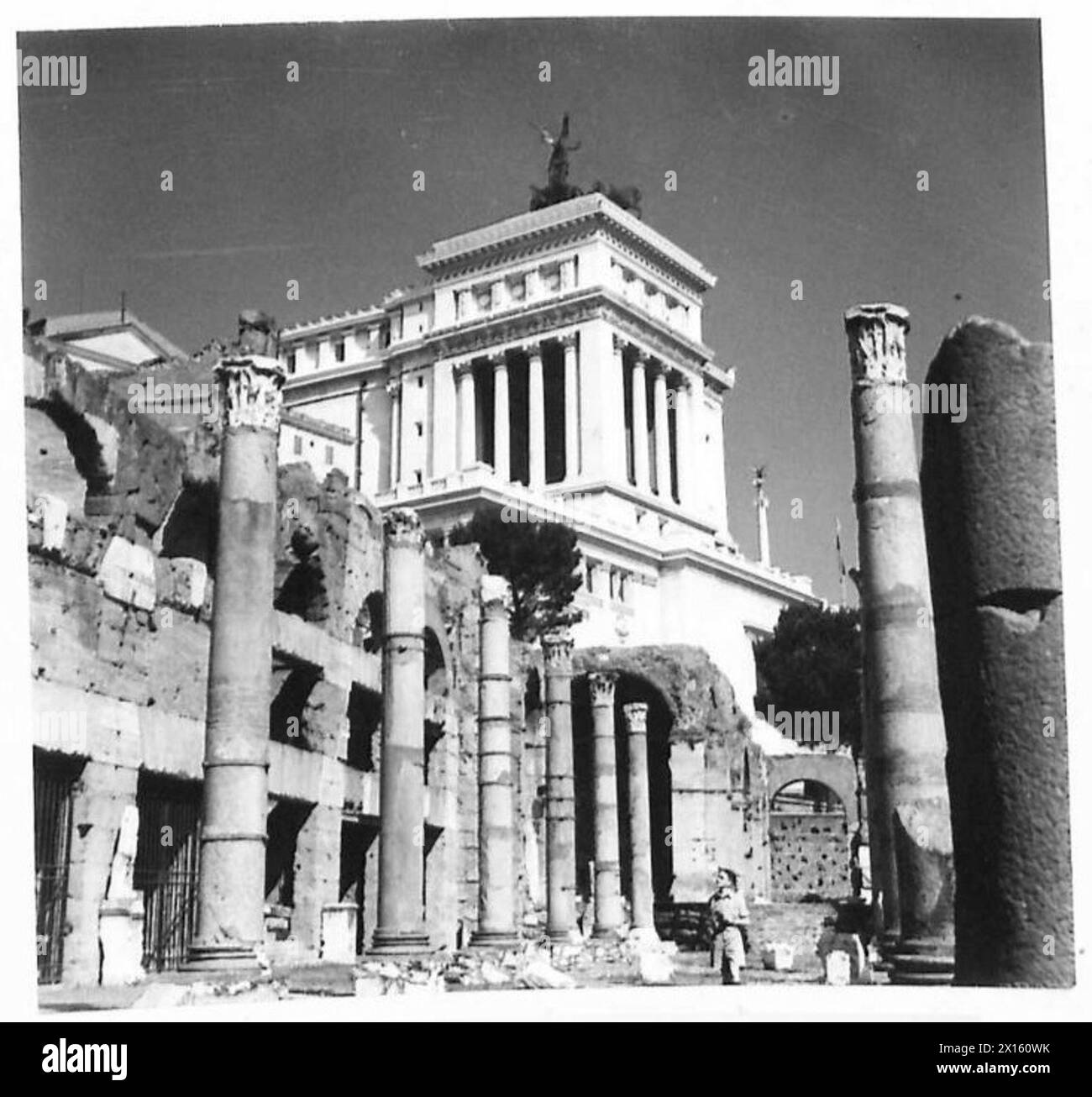 Gunner Smith inspecte le César's Forum à Rome avec le Mémorial Victor Emmanuel visible en arrière-plan, soulignant les monuments historiques. Banque D'Images