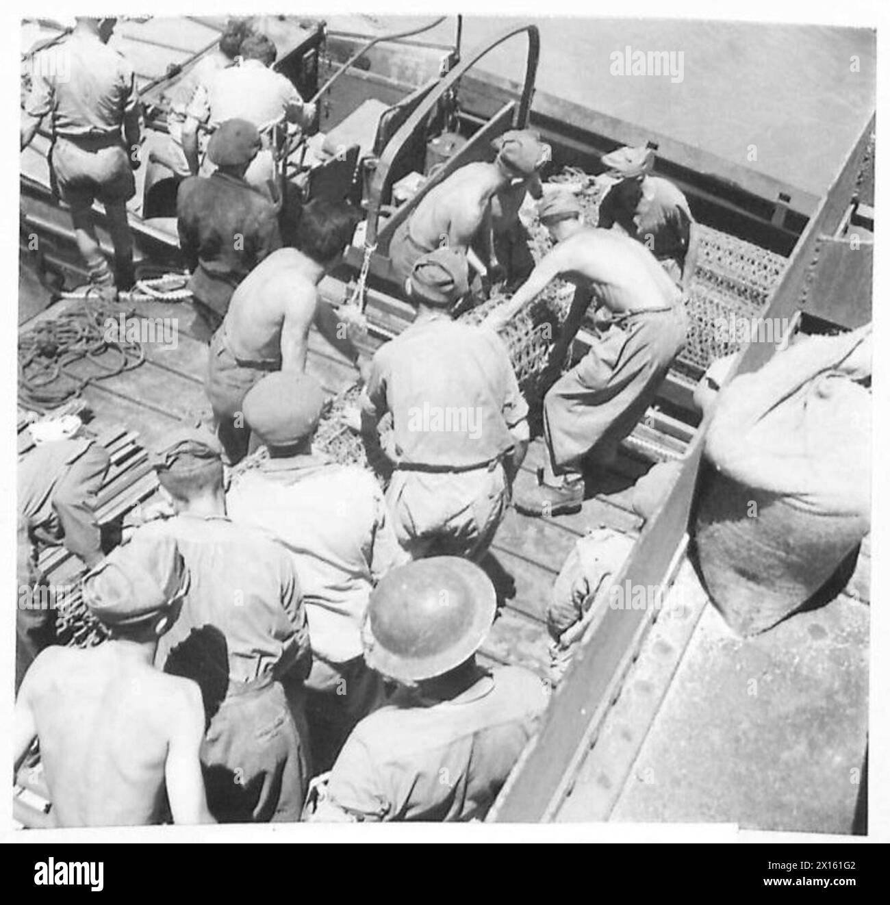 Les prisonniers italiens aident à décharger les fournitures d'une embarcation de débarquement vers un camion amphibie de 2 1/2 tonnes pendant l'invasion de la Sicile, illustrant les opérations logistiques et la coordination des troupes par l'armée britannique. Banque D'Images