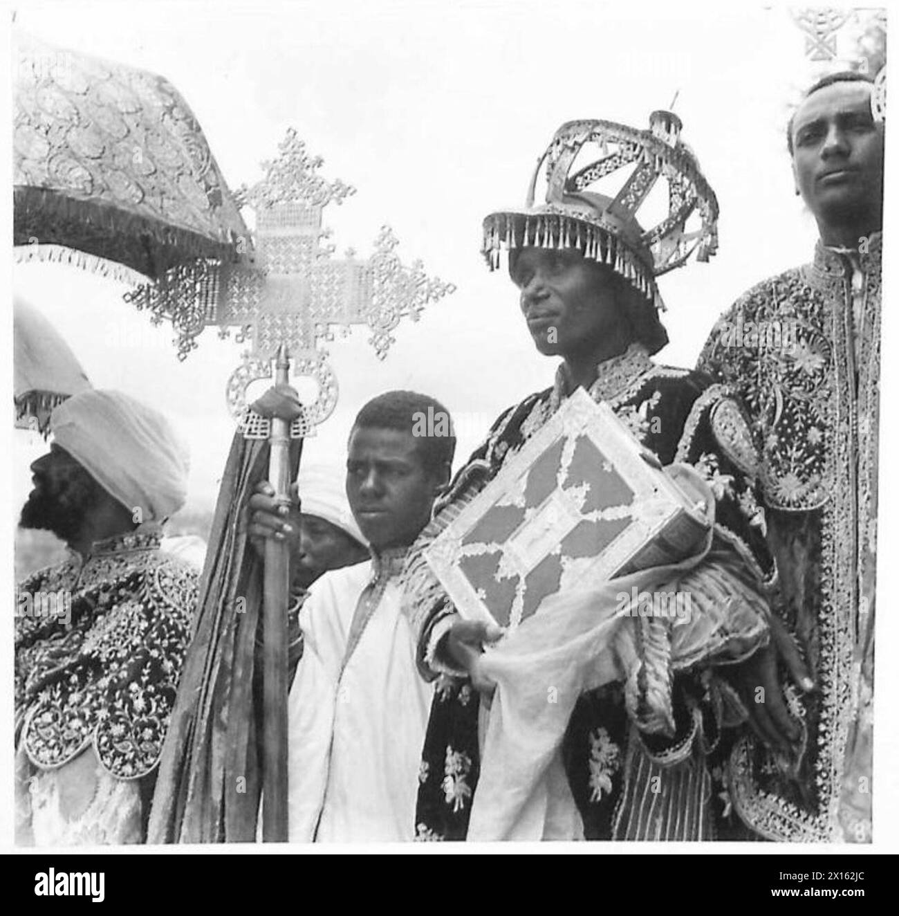 Haile Selassie entre à Addis-Abeba accompagné d’un diacre de l’Église abyssinienne en vêtements pleins. Il porte le Livre de l'Évangile, et un acolyte tient une croix processionnelle abyssinienne distinctive. La couronne portée est réservée aux occasions spéciales. Banque D'Images